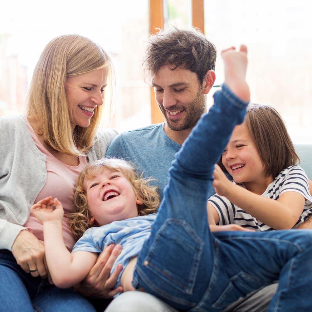 A family of four is smiling and laughing while sitting together.